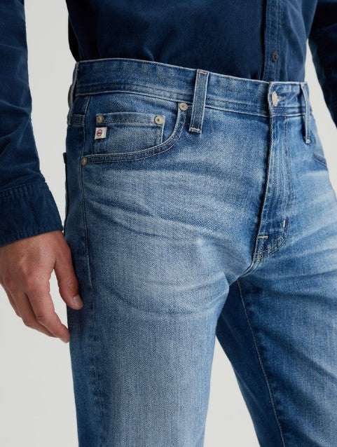 AG Tellis modern slim-fit denim jeans in medium indigo with tapered legs and subtle fading