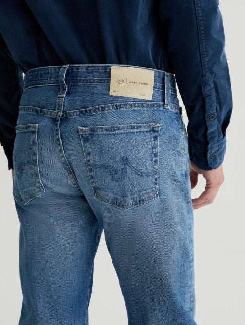 AG Tellis Aged Modern Slim Denim jeans in medium indigo with tapered legs and subtle fading