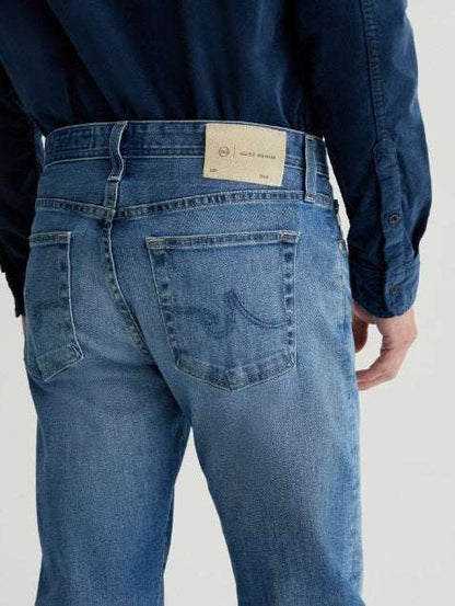 AG Tellis Aged Modern Slim Denim jeans in medium indigo with tapered legs and subtle fading