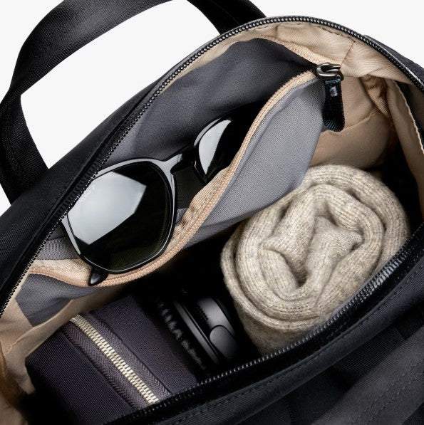 Bellroy Via Workpack black backpack open showing padded compartments with sunglasses and rolled sweater inside