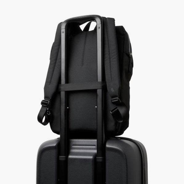 Black Bellroy Via Workpack backpack with padded straps mounted on suitcase handle for easy travel